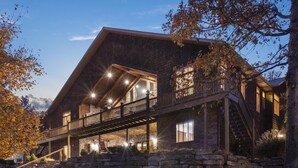 A large, multi-story log cabin with a prominent balcony and stone foundation. - The Lodge at Rock Canyon (Branson)