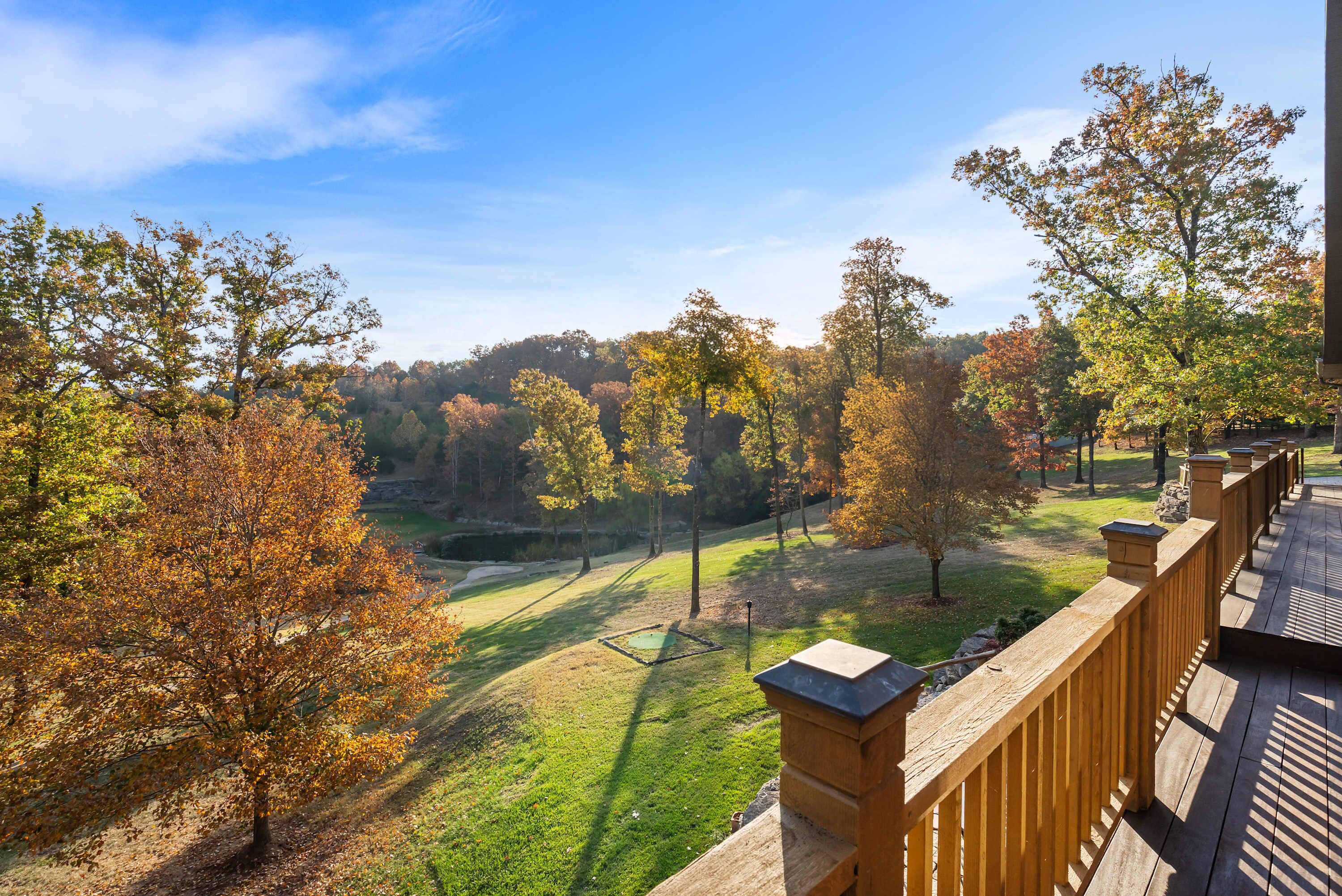 A wooden deck with a view of a park with trees and a golf course.