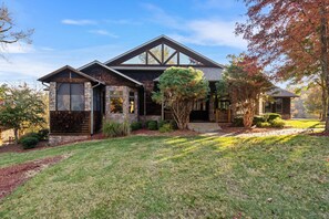 A modern two-story house with a stone facade, large windows, and a well-maintained lawn. - The Lodge at Rock Canyon (Branson)