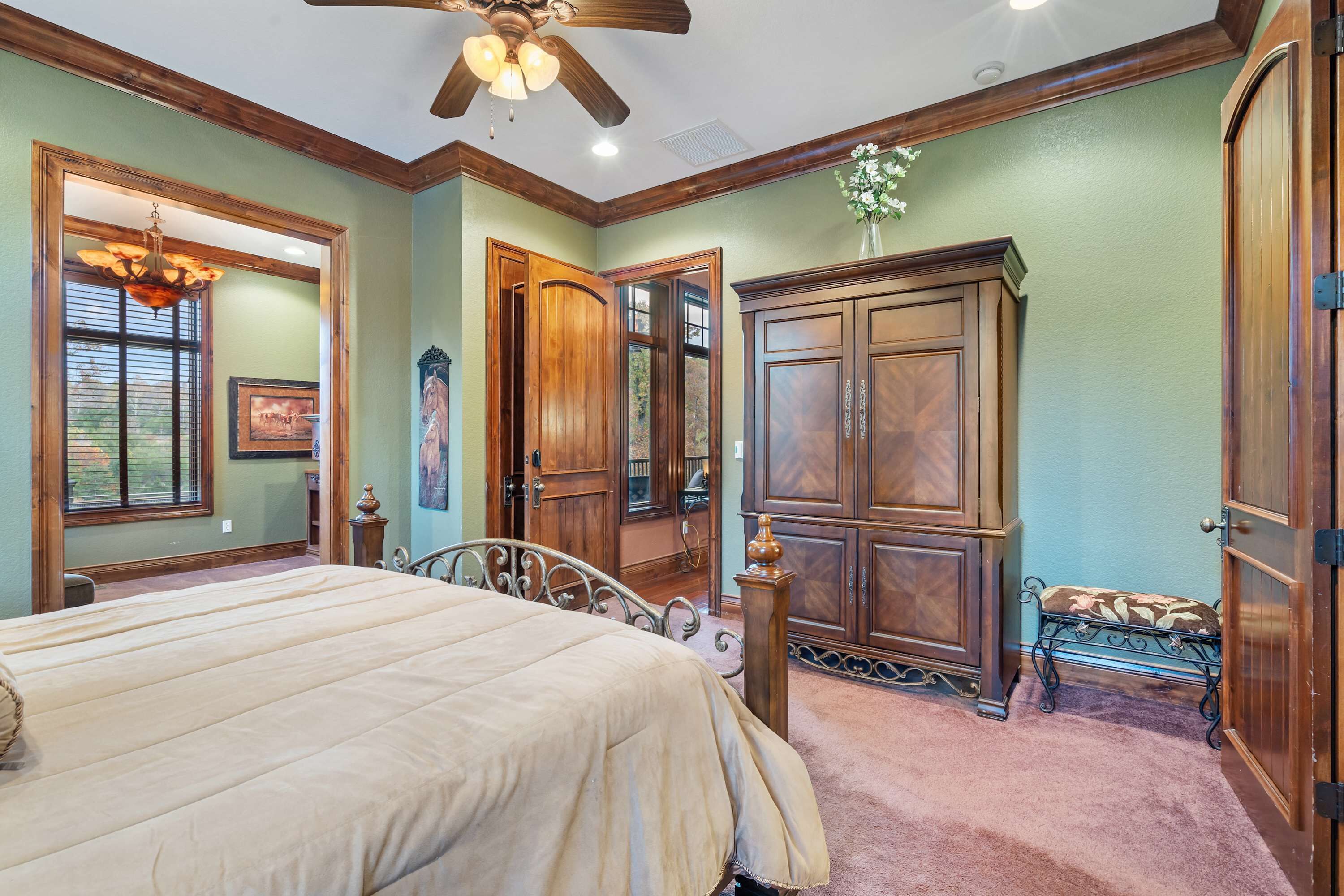 A bedroom with a bed, wooden wardrobe, and a ceiling fan.