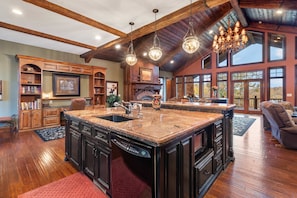 A spacious kitchen with a large island, wooden cabinetry, and a fireplace. - The Lodge at Rock Canyon (Branson)