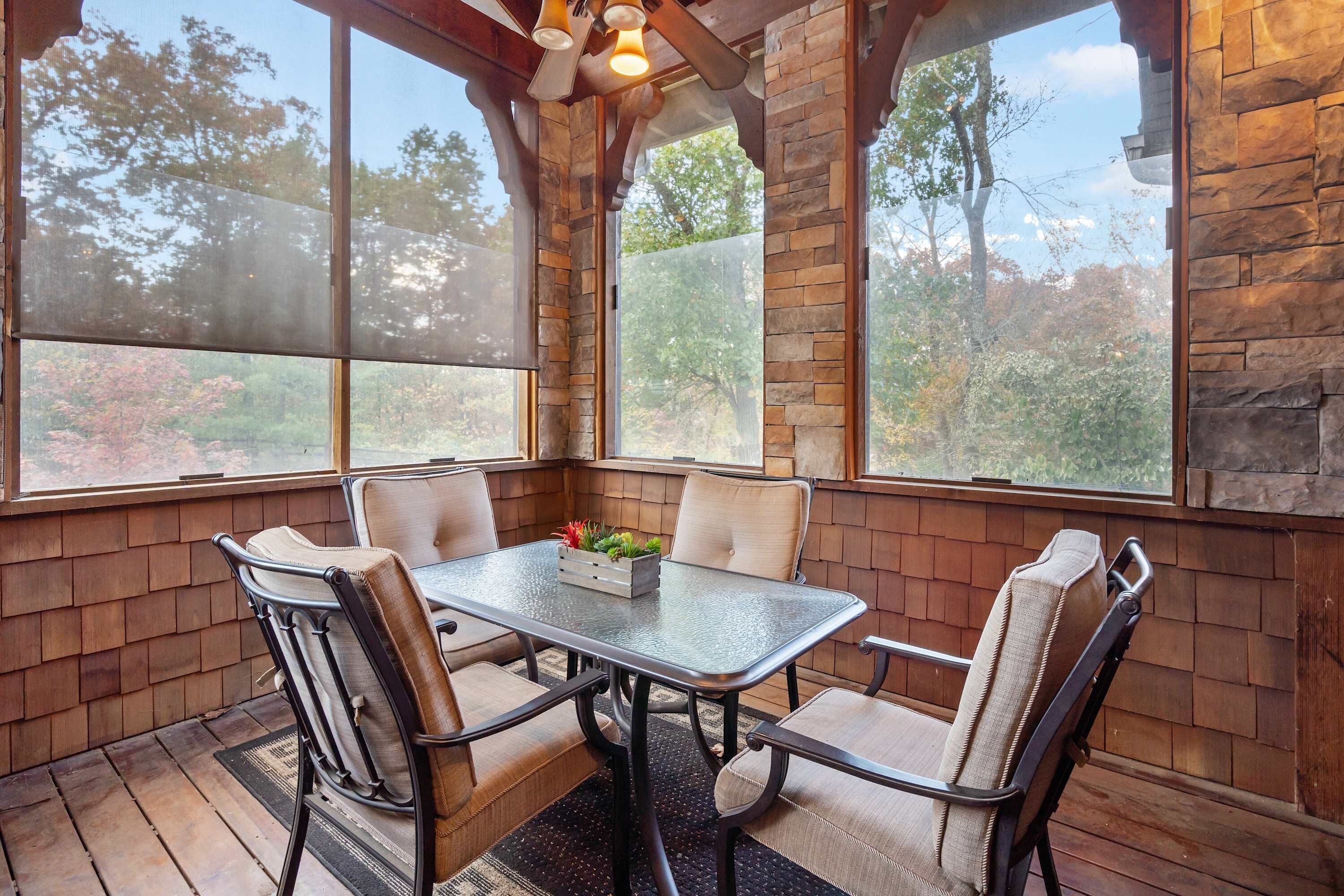 A corner dining area with a stone wall, large windows, and a table with four chairs.