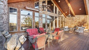 A spacious outdoor patio with stone walls, large windows, and a wooden ceiling. - The Lodge at Rock Canyon (Branson)