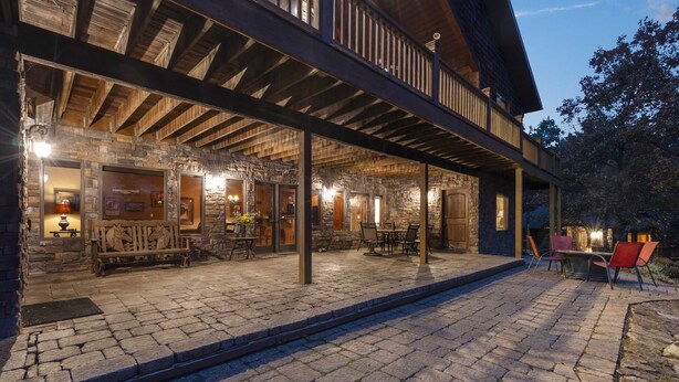Un patio couvert doté de murs en pierre, de mobilier en bois et d’un foyer.