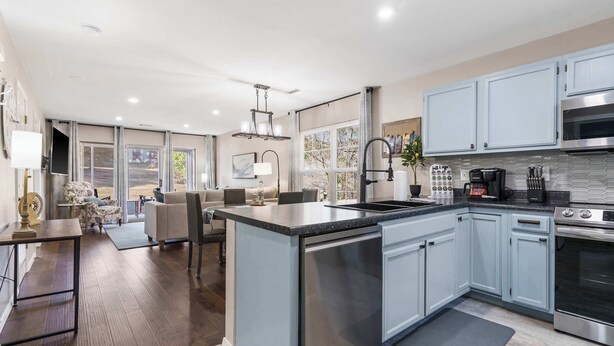 A modern kitchen with light blue cabinets, stainless steel appliances, and a central island. - Water's Edge & Golf Course View (Branson)