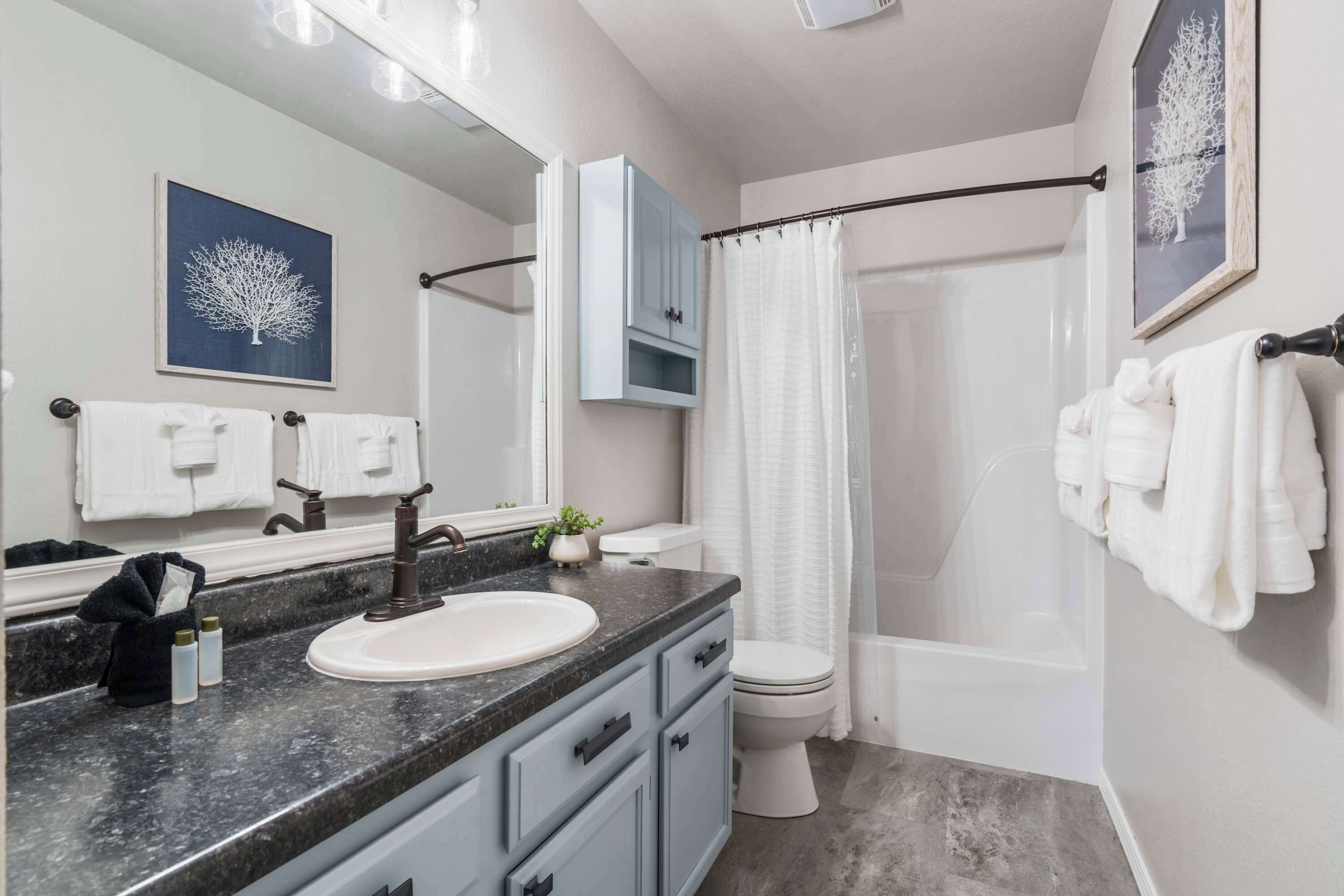 A bathroom with a sink, mirror, cabinet, toilet, and shower curtain.