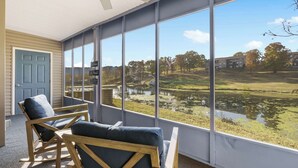 A room with large windows, two wooden chairs, and a door. - Water's Edge & Golf Course View (Branson)