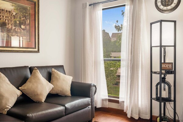 A room with a black leather sofa, white curtains, a framed picture, and a black bookshelf with a sign that says "HOPE". - Banta House Retreat at the Pointe (Branson)
