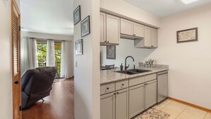 A modern kitchen with light-colored cabinets, a granite countertop, and a built-in oven. - Banta House Retreat at the Pointe (Branson)