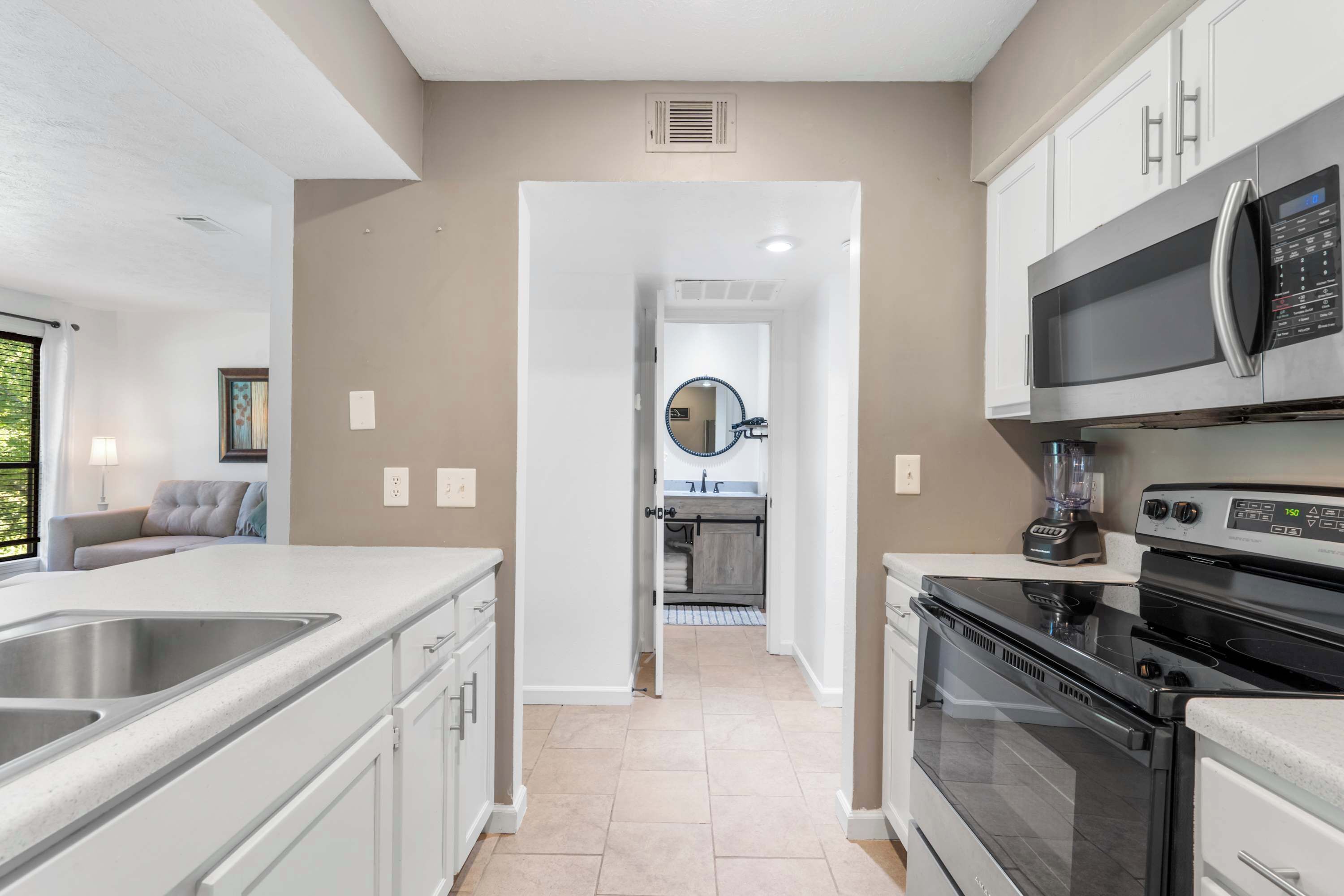 A modern kitchen with white cabinets, stainless steel appliances, and a central island.