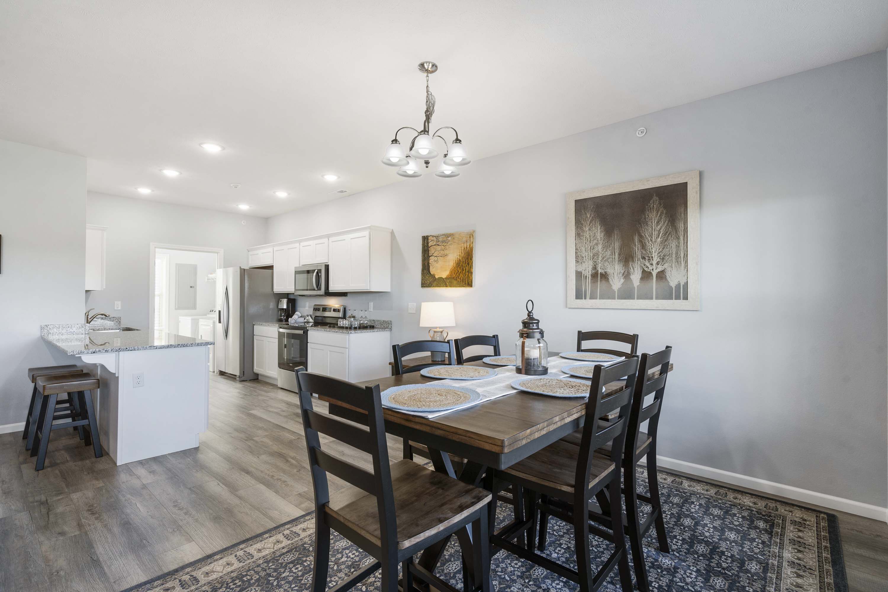 A modern kitchen with white cabinets, a central island, and a dining area with dark wooden chairs and a table.