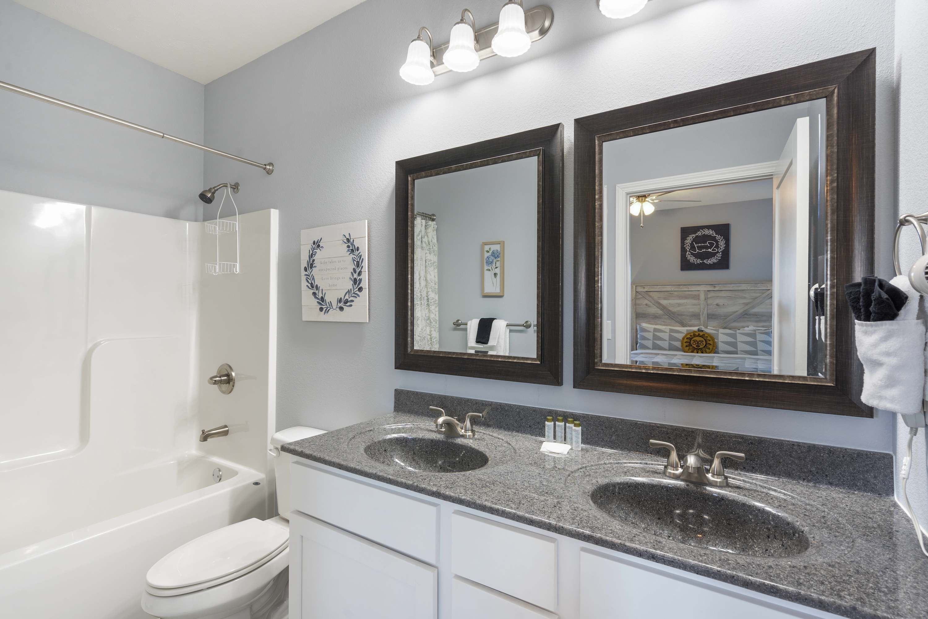 Une salle de bain avec une baignoire blanche, deux lavabos et un grand miroir.