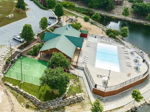 A sports complex with a tennis court, a pool, and a covered pavilion.
