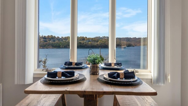 A dining table set for four with a view of a lake and hills in the background. - Lakescape at The Getaways (Kimberling City)