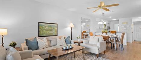 A modern living room with a sofa, coffee table, and dining area with chairs and a table.