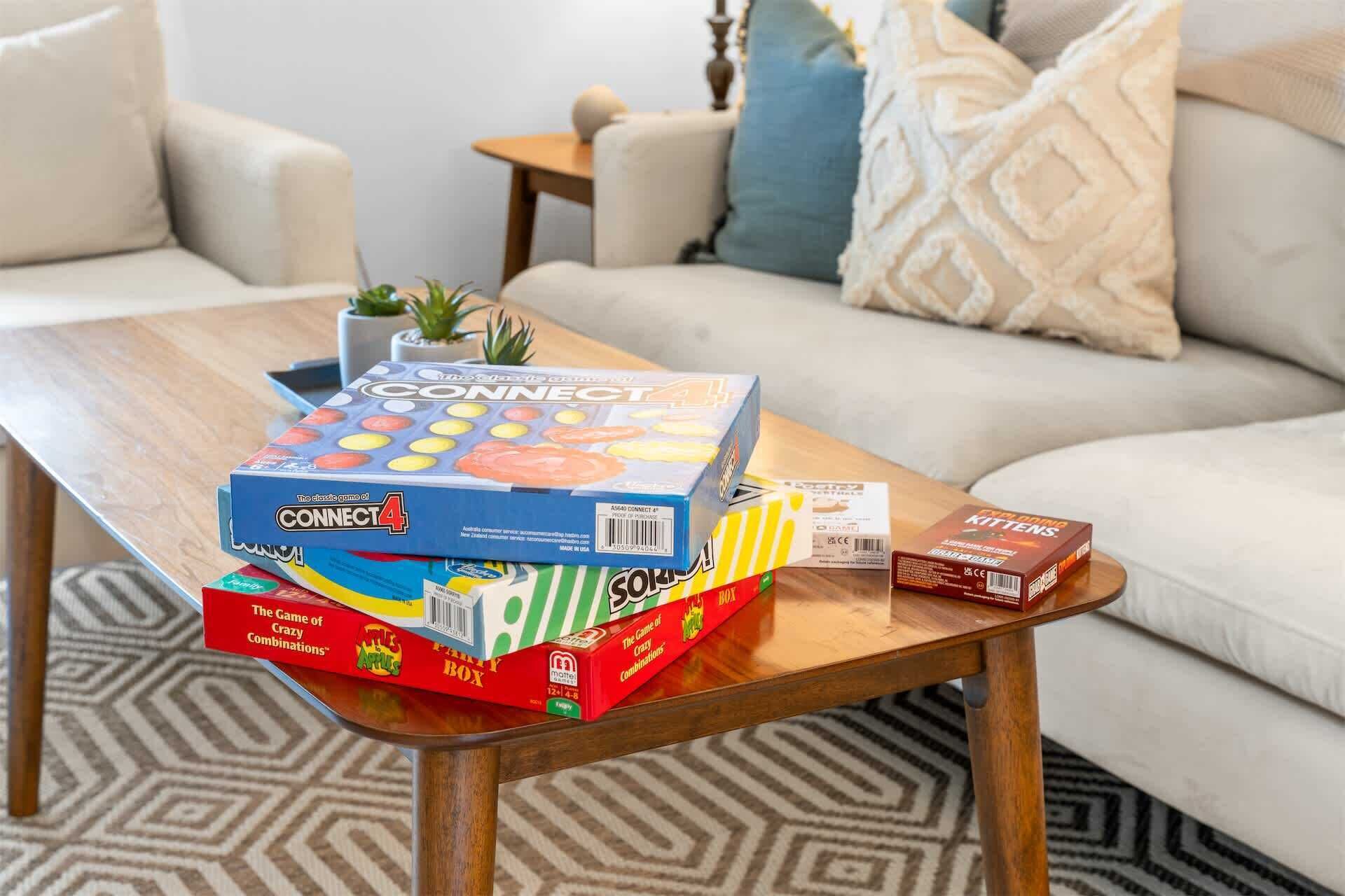 A living room with a wooden coffee table holding board games and a book.