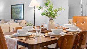 A dining area with a table set for four, a vase with green foliage, and a lamp. - Royal Ridge Modern Condo for 4 (Branson)