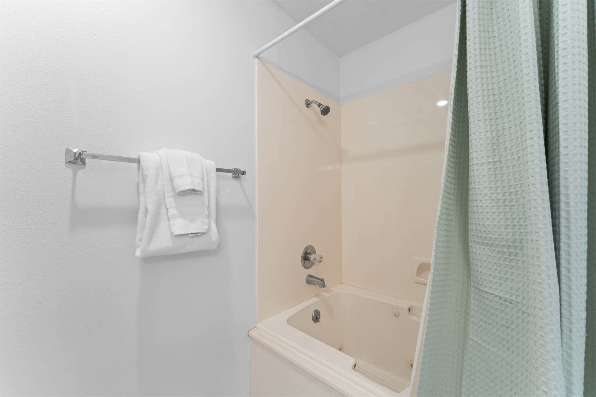 A bathroom with a bathtub, a towel rack with a towel, and a shower curtain.