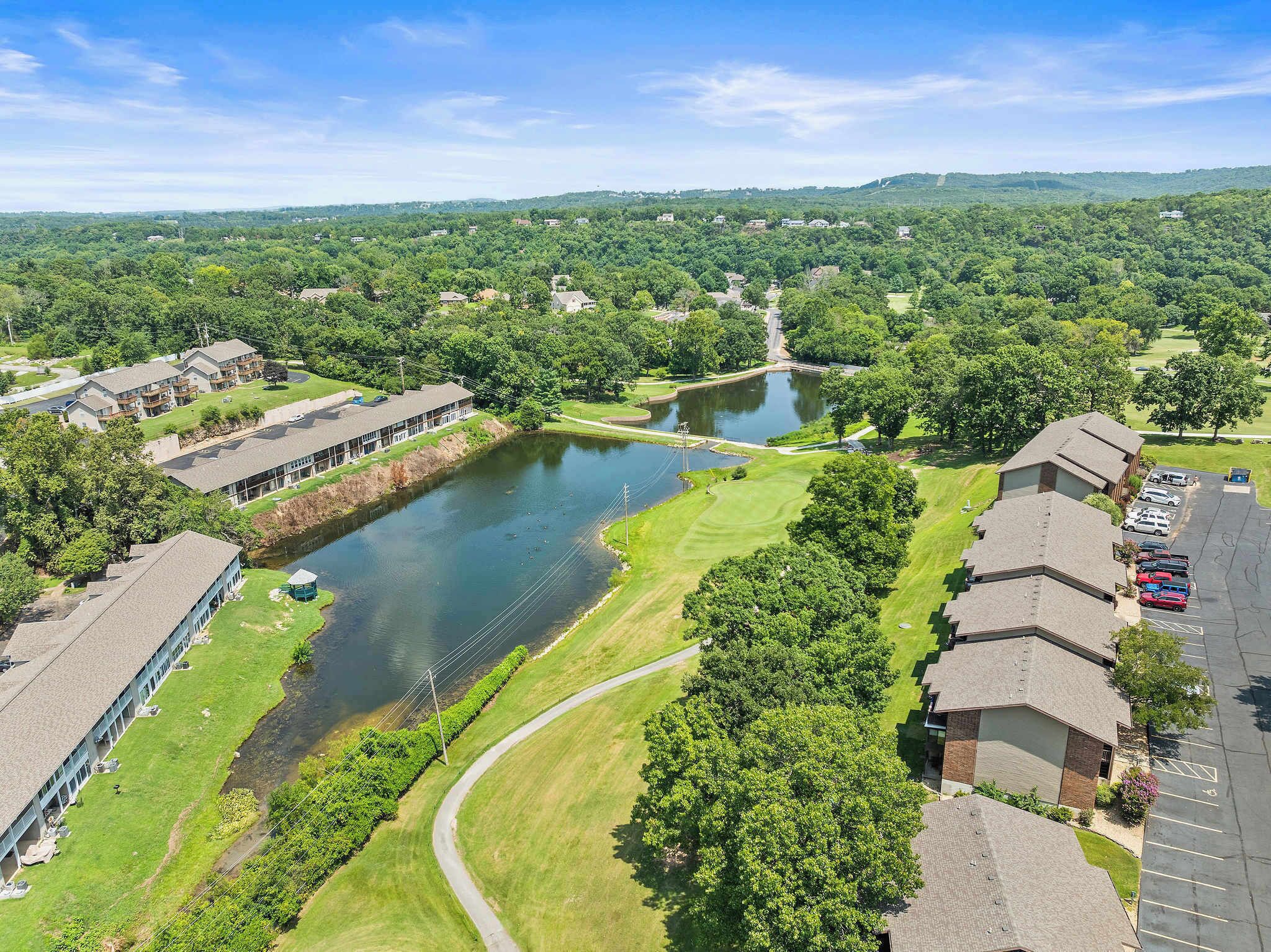 A residential area with a lake, houses, and a golf course.