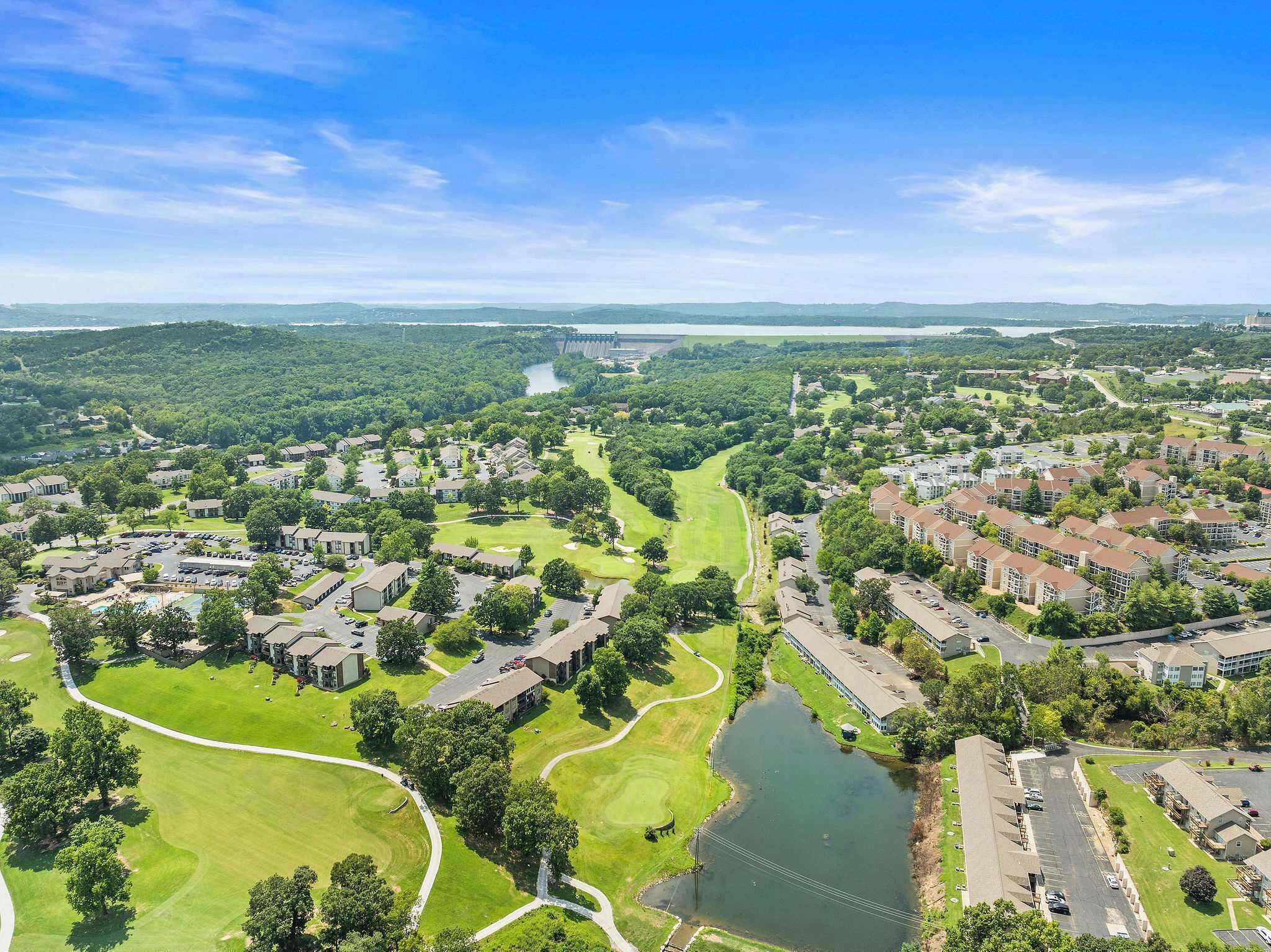 An aerial view of a residential area with houses, a golf course, and a large body of water.