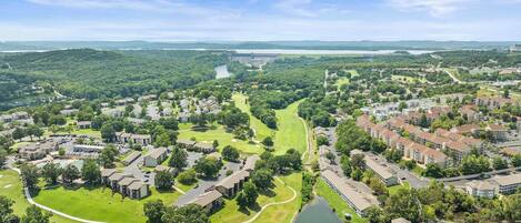An aerial view of a residential area with houses, a golf course, and a large body of water.