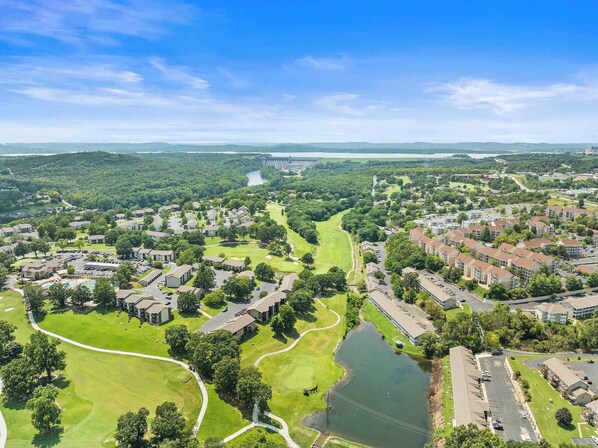 An aerial view of a residential area with houses, a golf course, and a large body of water. - Pointe Royale Getaway - Fore 4 (Branson)