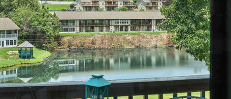 A view of a lakeside property with a gazebo, a pond, and a building with balconies.