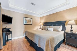 A neatly arranged bedroom with a large bed, bedside tables, a flat-screen TV, and a framed picture on the wall. - Pointe Royale Getaway - Fore 4 (Branson)