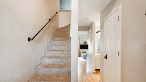 A staircase with a handrail and a wooden floor leading to a room with a white door and a kitchen area visible in the background. - Scenic Spot Vacation Property (Branson)