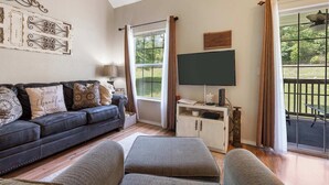 A living room with a sofa, a television, and a window with curtains. - Scenic Spot Vacation Property (Branson)