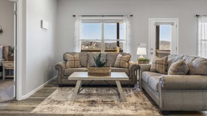 Ein Wohnzimmer mit zwei Sofas, einem Couchtisch und Blick ins Freie.