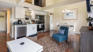 Una cocina amplia con electrodomésticos modernos, un comedor con un sofá azul y una escalera que sube a un nivel superior.