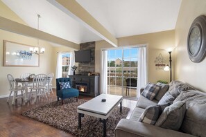 A living room with a fireplace, a sofa, a coffee table, and a dining area with chairs. - Pondside Paradise Retreat (Branson)