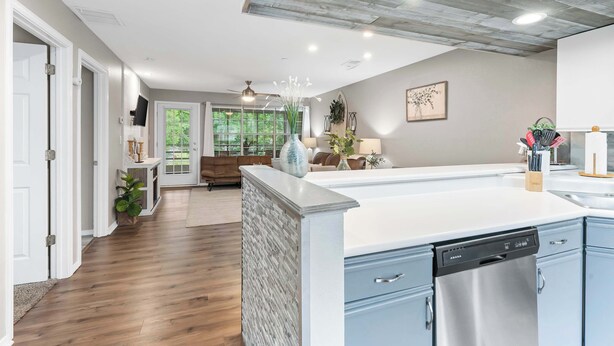 A modern kitchen with a dishwasher, a dining area with a table and chairs, and a living room with a sofa and a coffee table. - Lakeside Bliss Retreat 2 BDR (Branson)