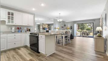 A modern kitchen with white cabinetry, a central island, and a dining area with chairs.