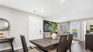 A modern dining area with a dark wood table and chairs, a vase with greenery, and a painting on the wall. - Earl Grey Escape - Chic 3 Bdr! (Branson)