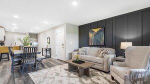A modern living room with a sofa, armchair, coffee table, and dining area. - Earl Grey Escape - Chic 3 Bdr! (Branson)