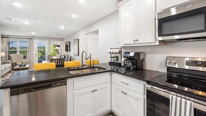 A modern kitchen with white cabinets, a black countertop, stainless steel appliances, and a built-in oven. - Earl Grey Escape - Chic 3 Bdr! (Branson)