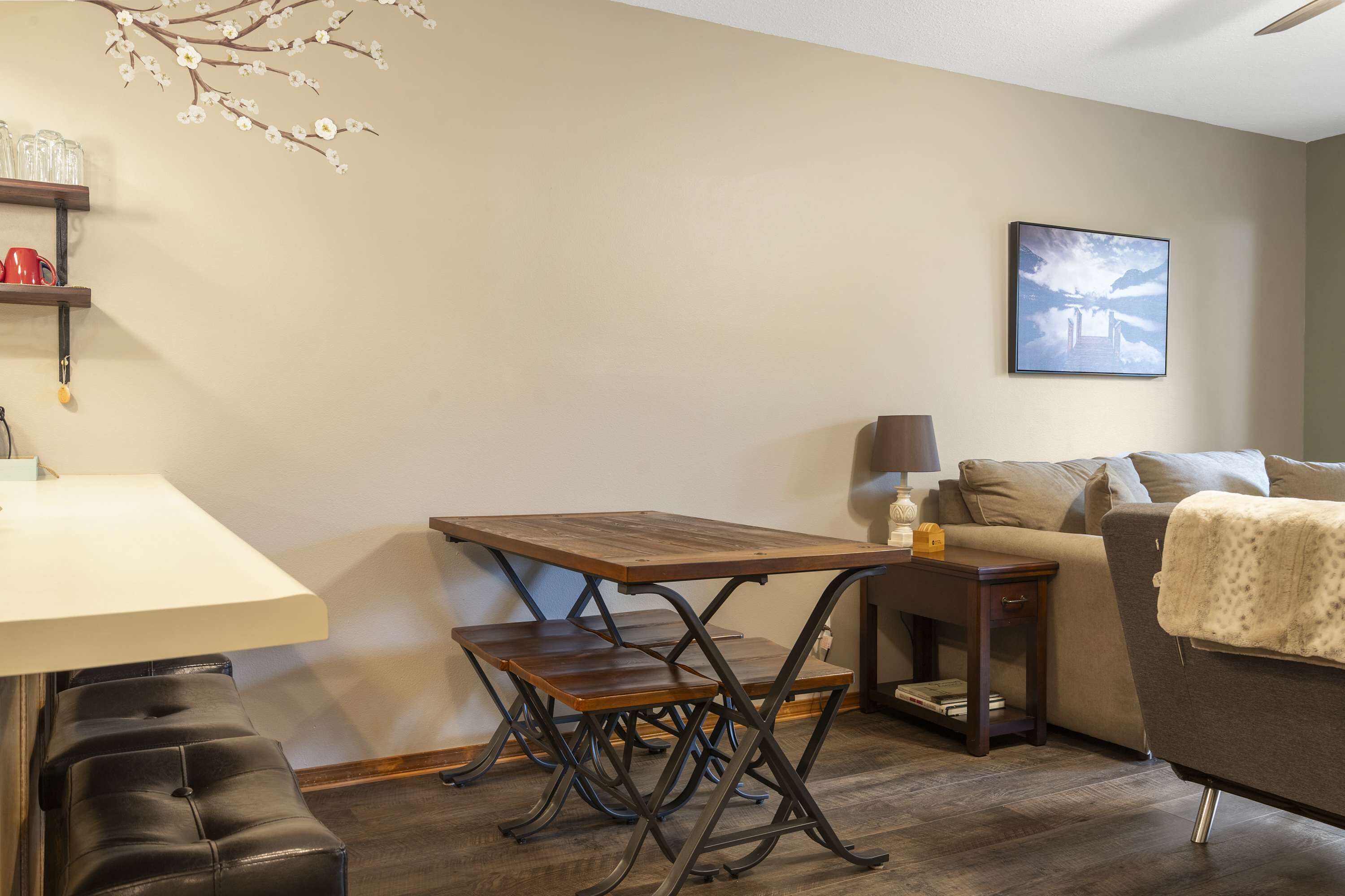 A cozy living room with a wooden dining table, two cushioned chairs, a sofa, and a coffee table.