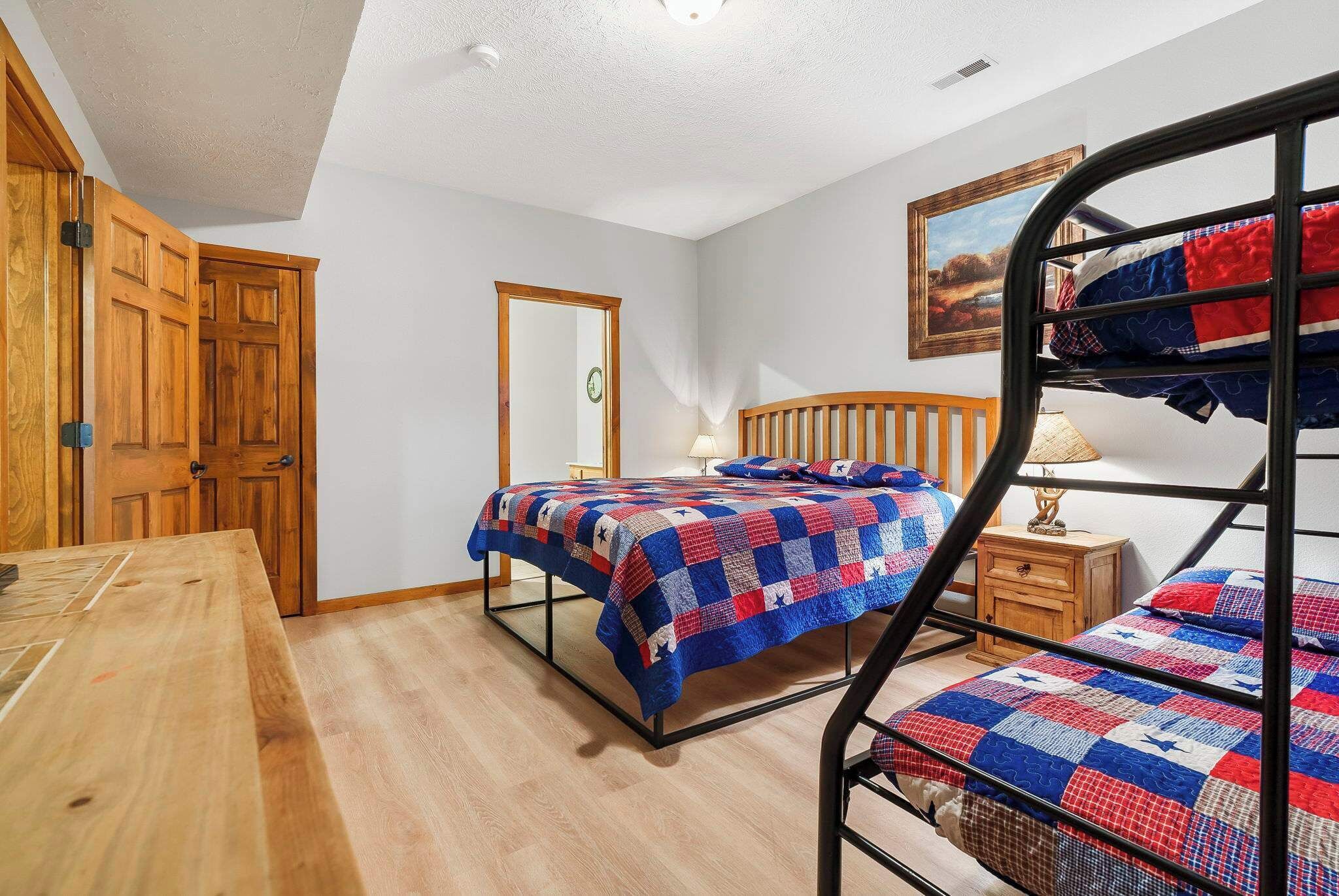 Un dormitorio con una cama litera, una mesa de madera, un armario de madera y un espejo en la pared.