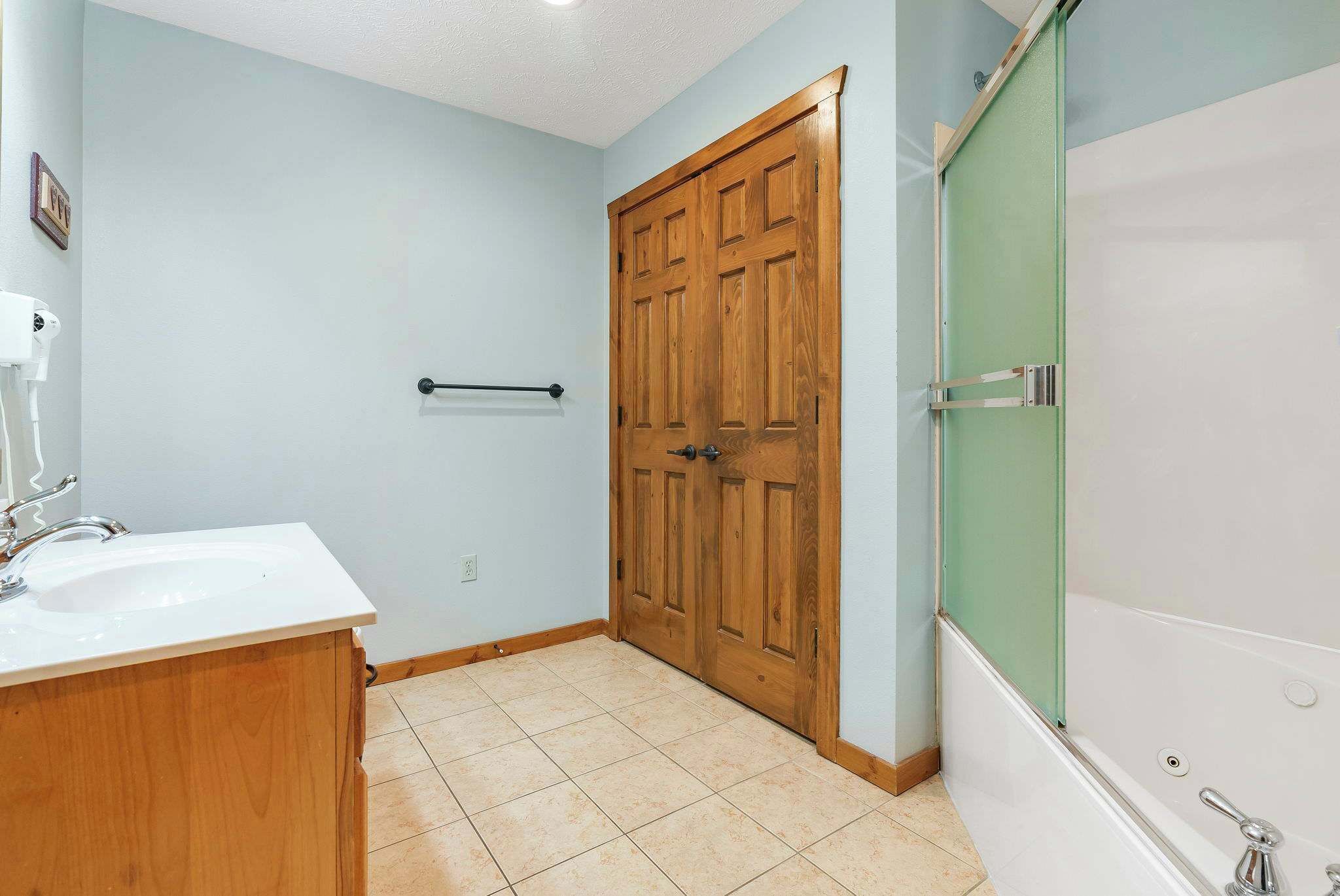 A bathroom with a wooden door, a white sink, and a bathtub.