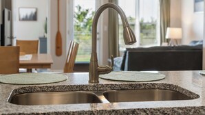 Une cuisine dotée d’un évier en acier inoxydable, de plans de travail en granit et d’un robinet moderne.