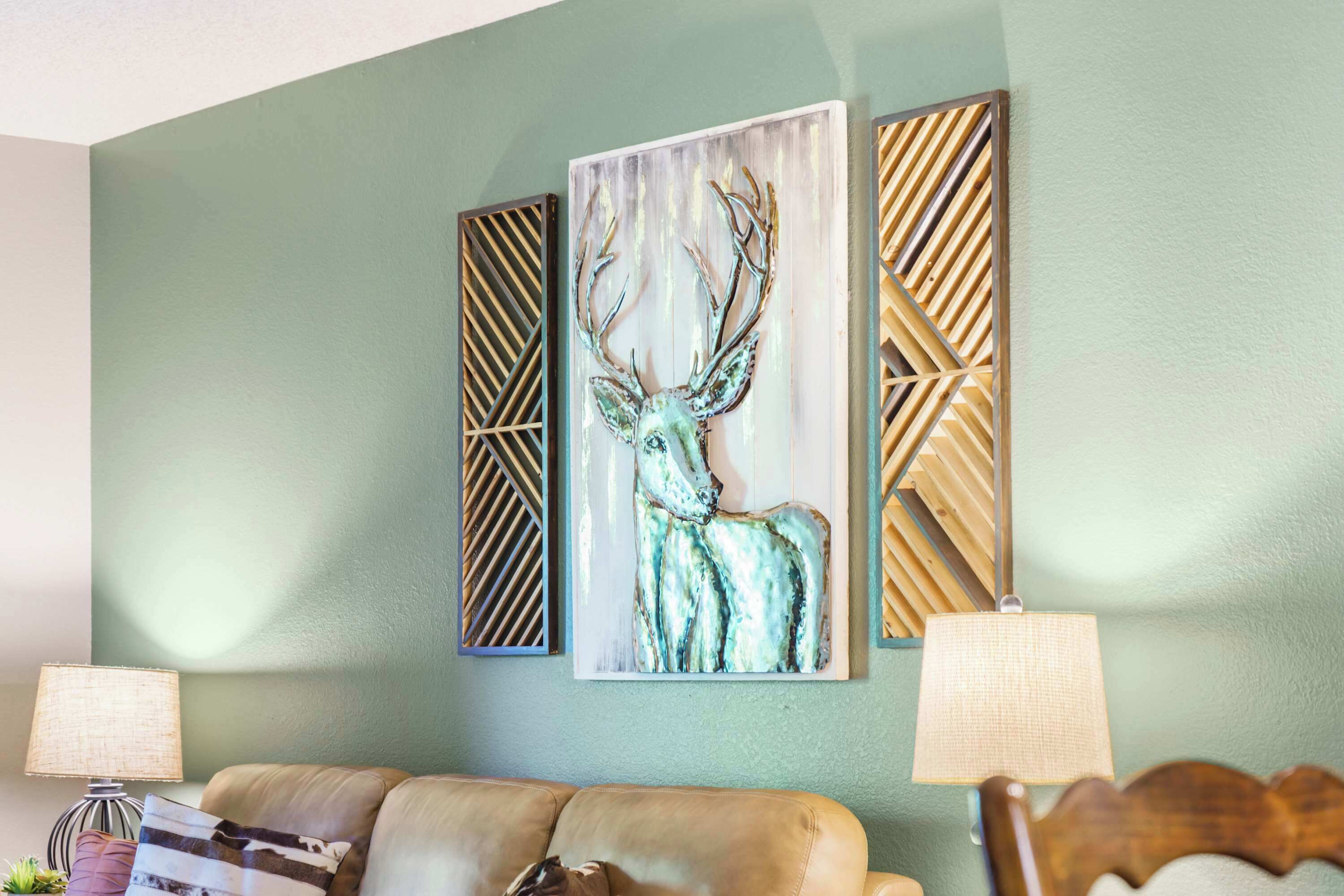 Una sala de estar con una pared verde, un sofá de cuero marrón y dos lámparas fijadas a la pared.