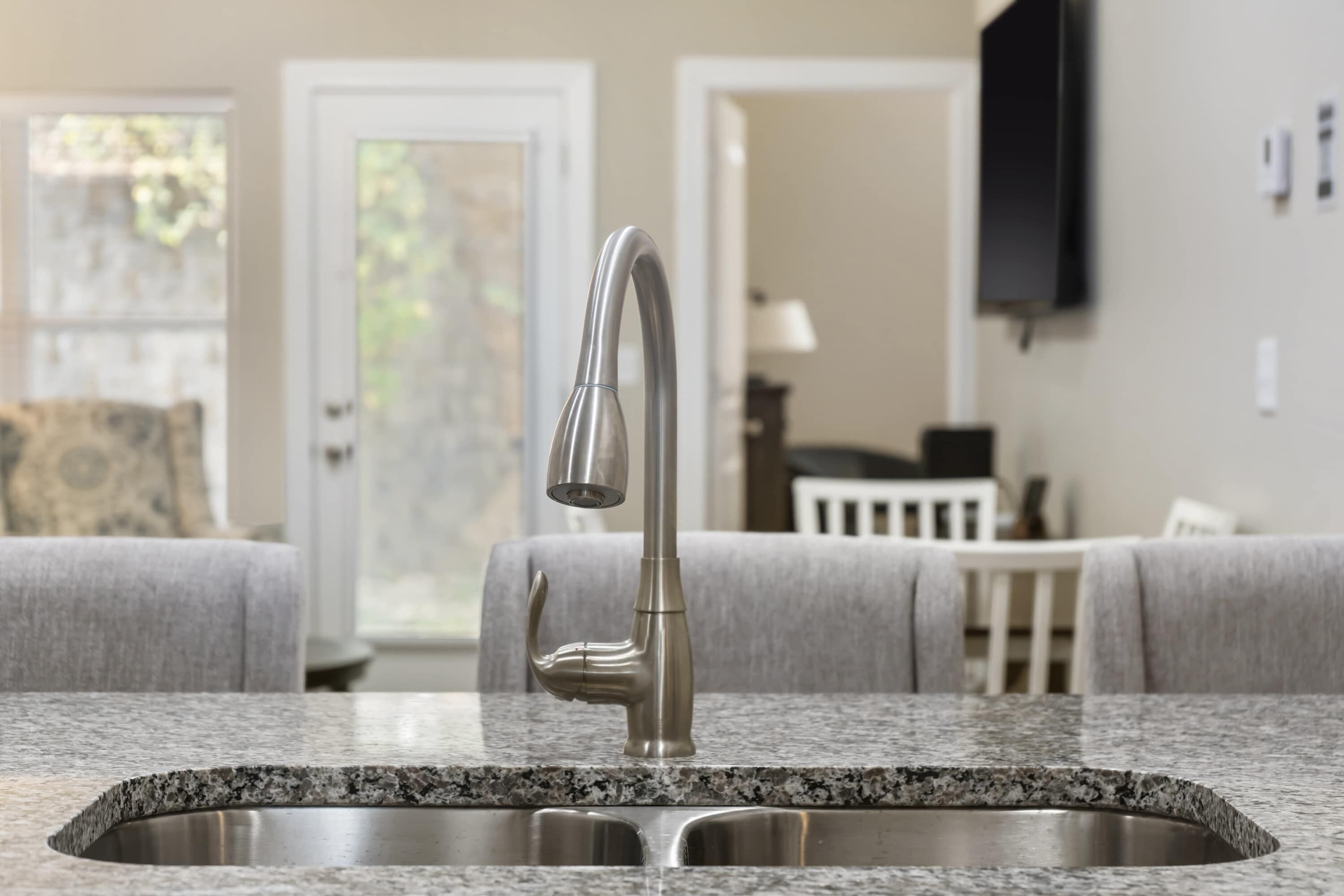 A kitchen with a granite countertop and a stainless steel sink.