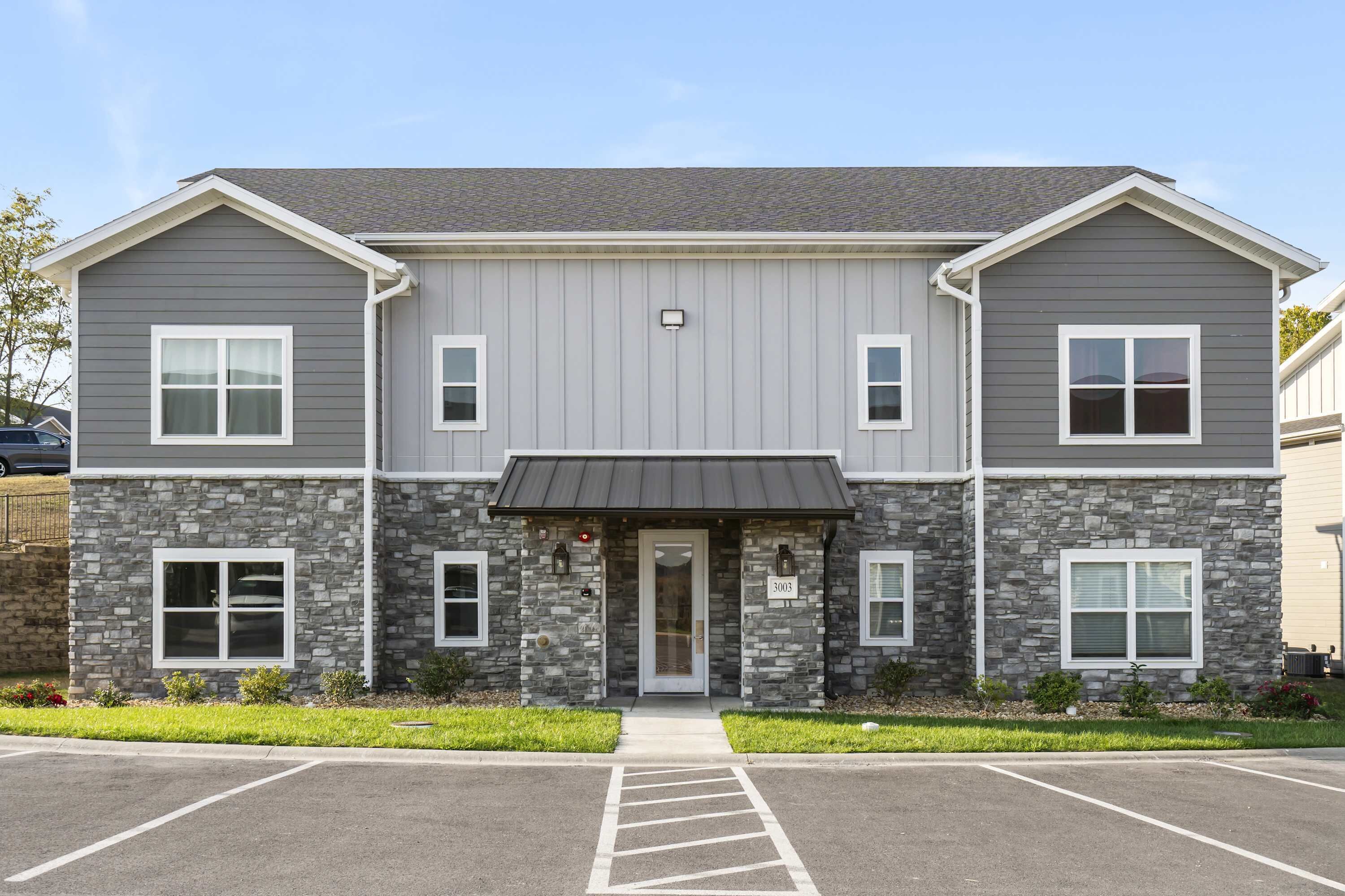 A two-story building with a stone facade and a flat roof.