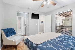 A bedroom with a bed, a chair, a ceiling fan, a TV, and a window with blinds. - Branson Sunny Daze - Sleeps 4 (Branson)