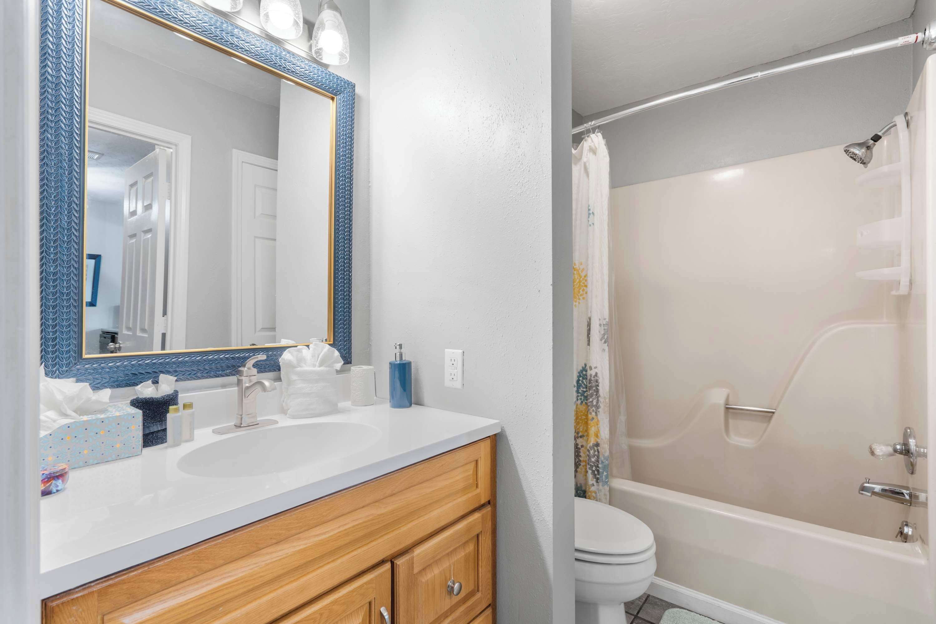 A bathroom with a white sink, wooden vanity, and a shower with a beige wall and a white curtain.