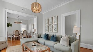 A living room with a sectional sofa, a glass coffee table, and a chandelier.