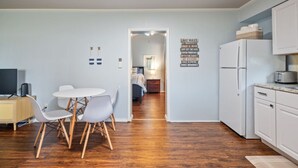 Una cocina compacta con zona de comedor, televisor y refrigerador.