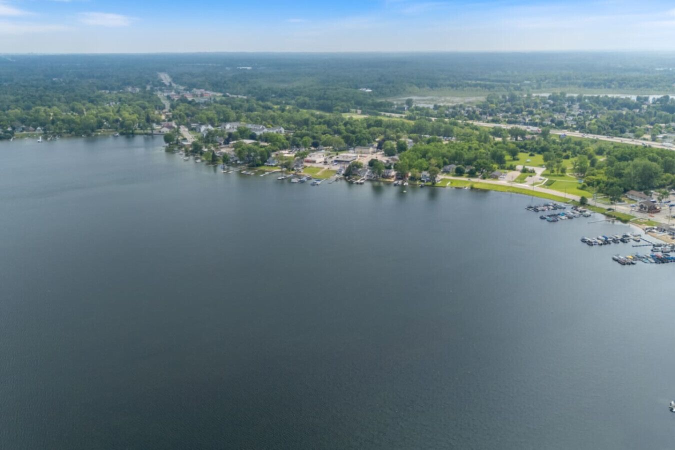 An aerial view of a lakeside town with a marina, residential areas, and a park.